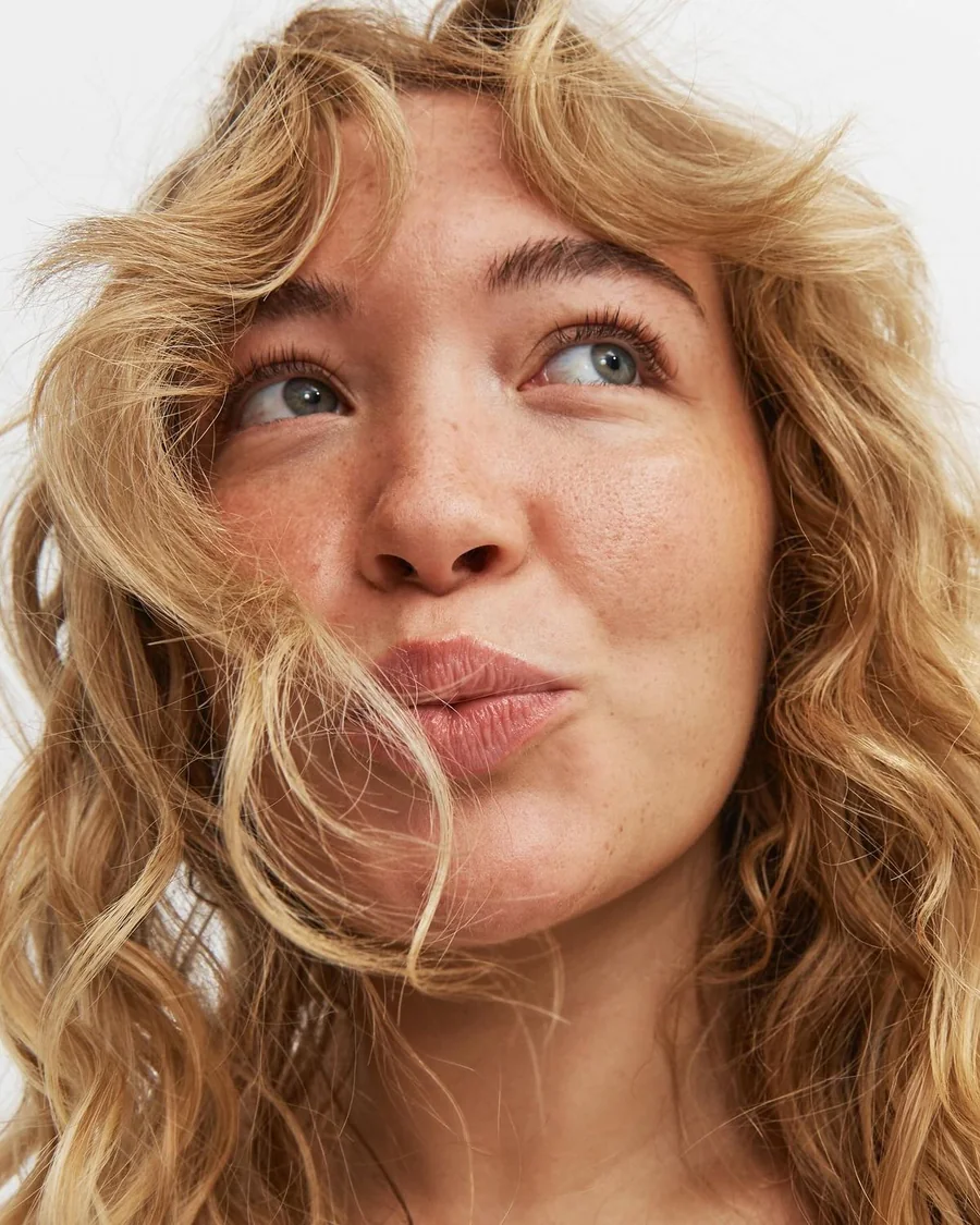 Close-up of a curly-haired woman looking upward