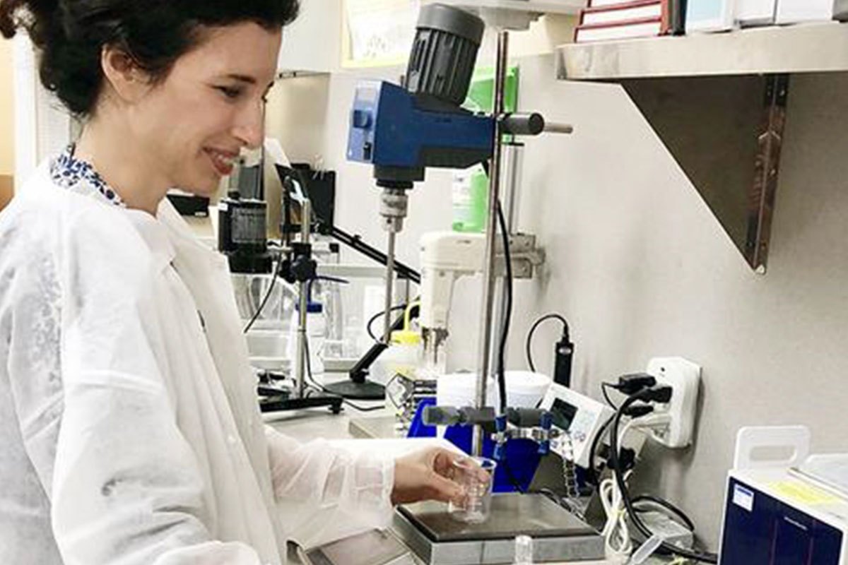 Kate Solomon mixes formula with lab equipment while smiling.