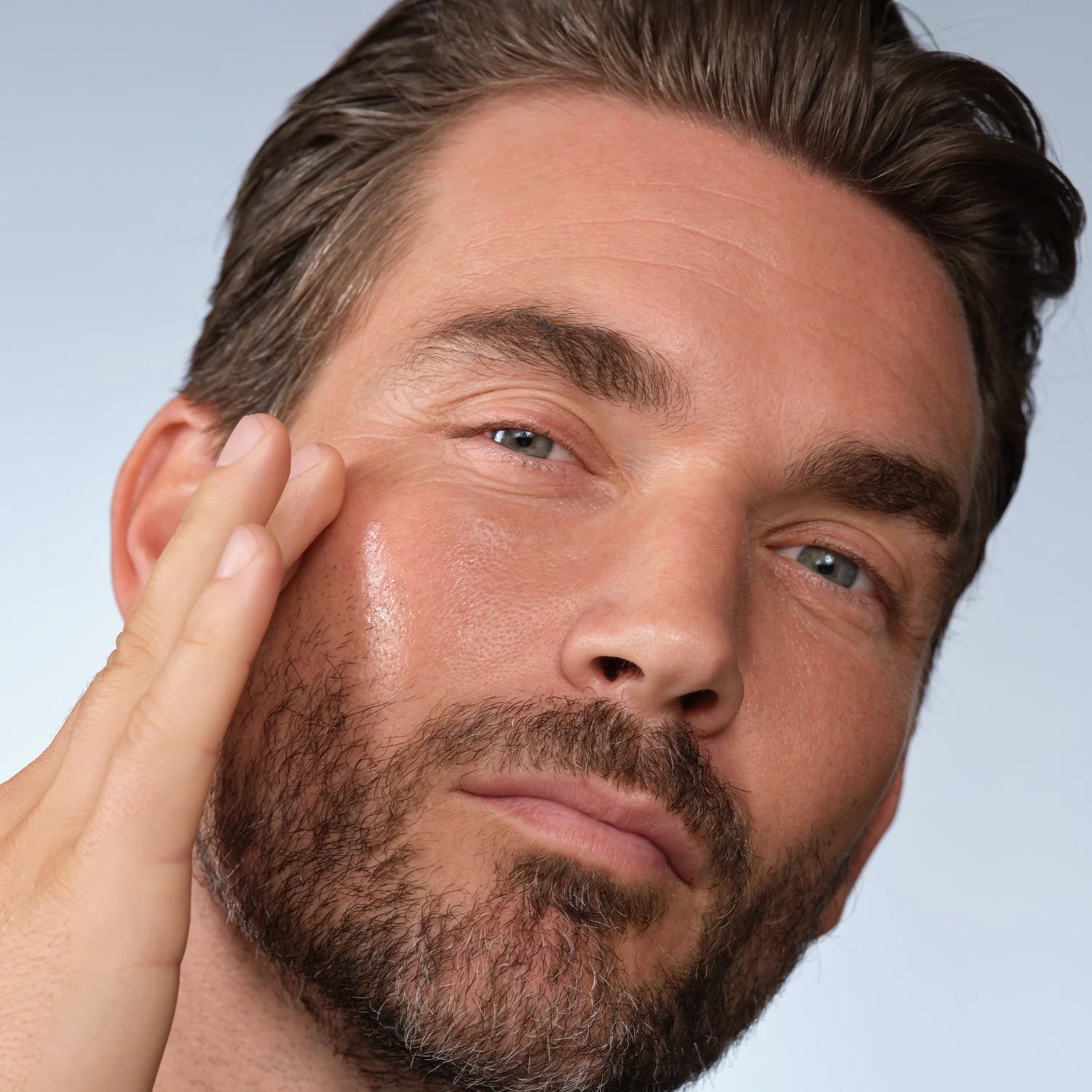 A bearded man pats Caldera plus Lab serum onto his cheek.