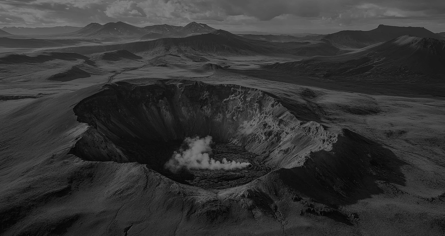 Black and white aerial view of a volcanic crater landscape.