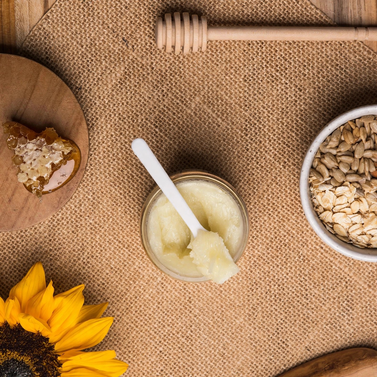 Overhead view of honey, oats and balm arranged on burlap.