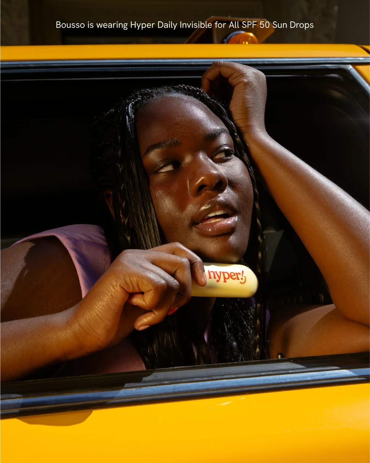 Woman leans from yellow taxi holding Hyper bottle.