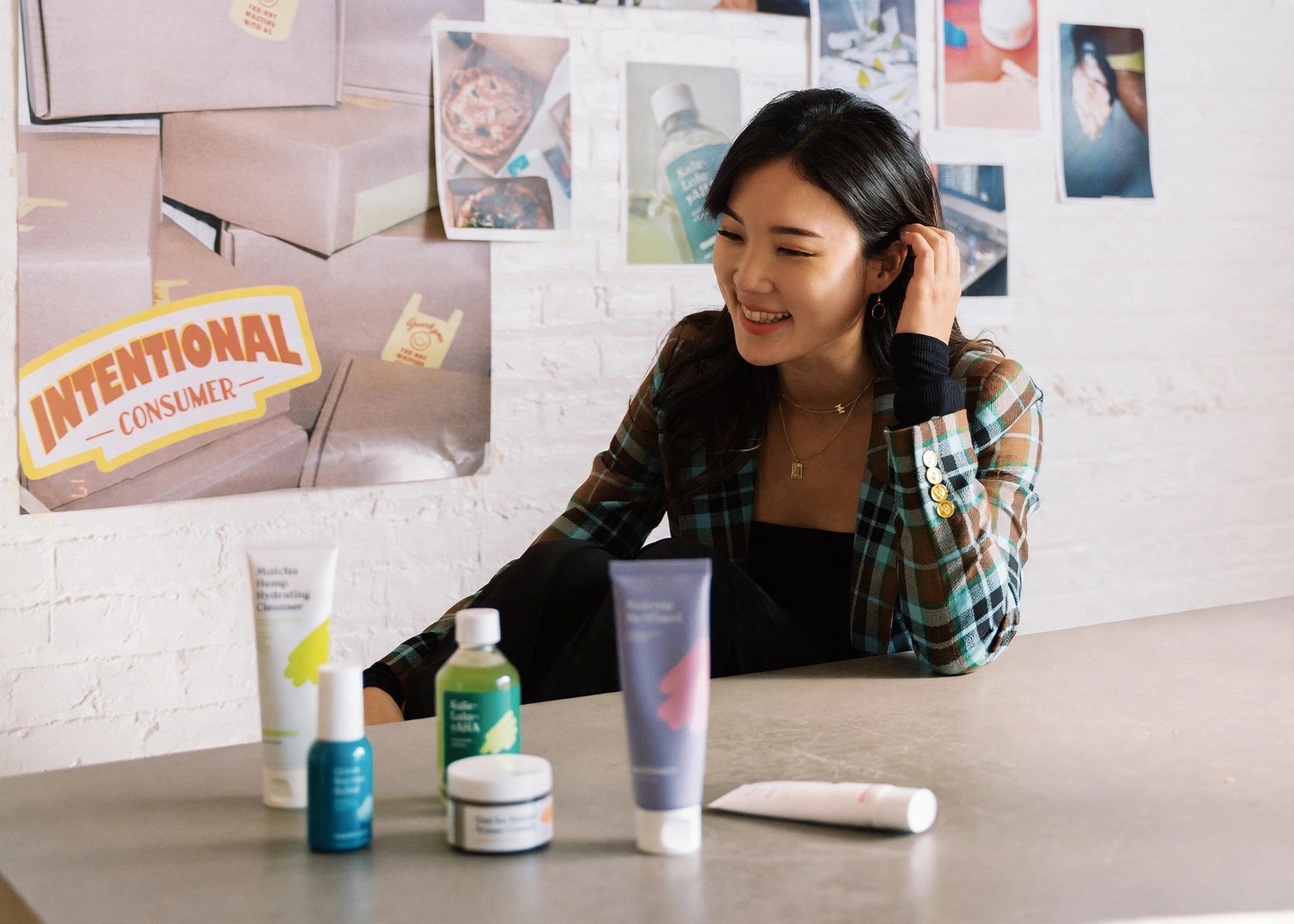 Founder Liah Yoo smiles seated behind a table of products.