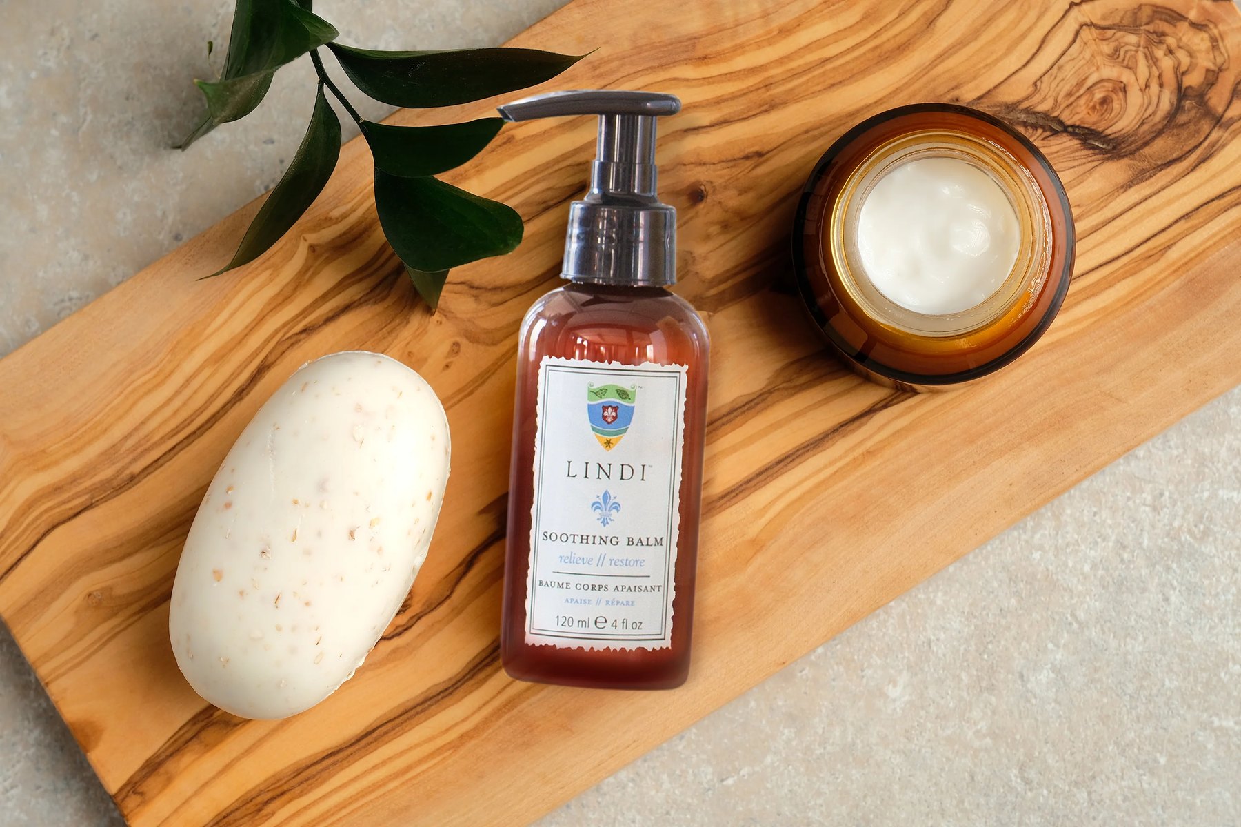 Lindi Soothing Balm pump bottle beside open balm jar on wood.