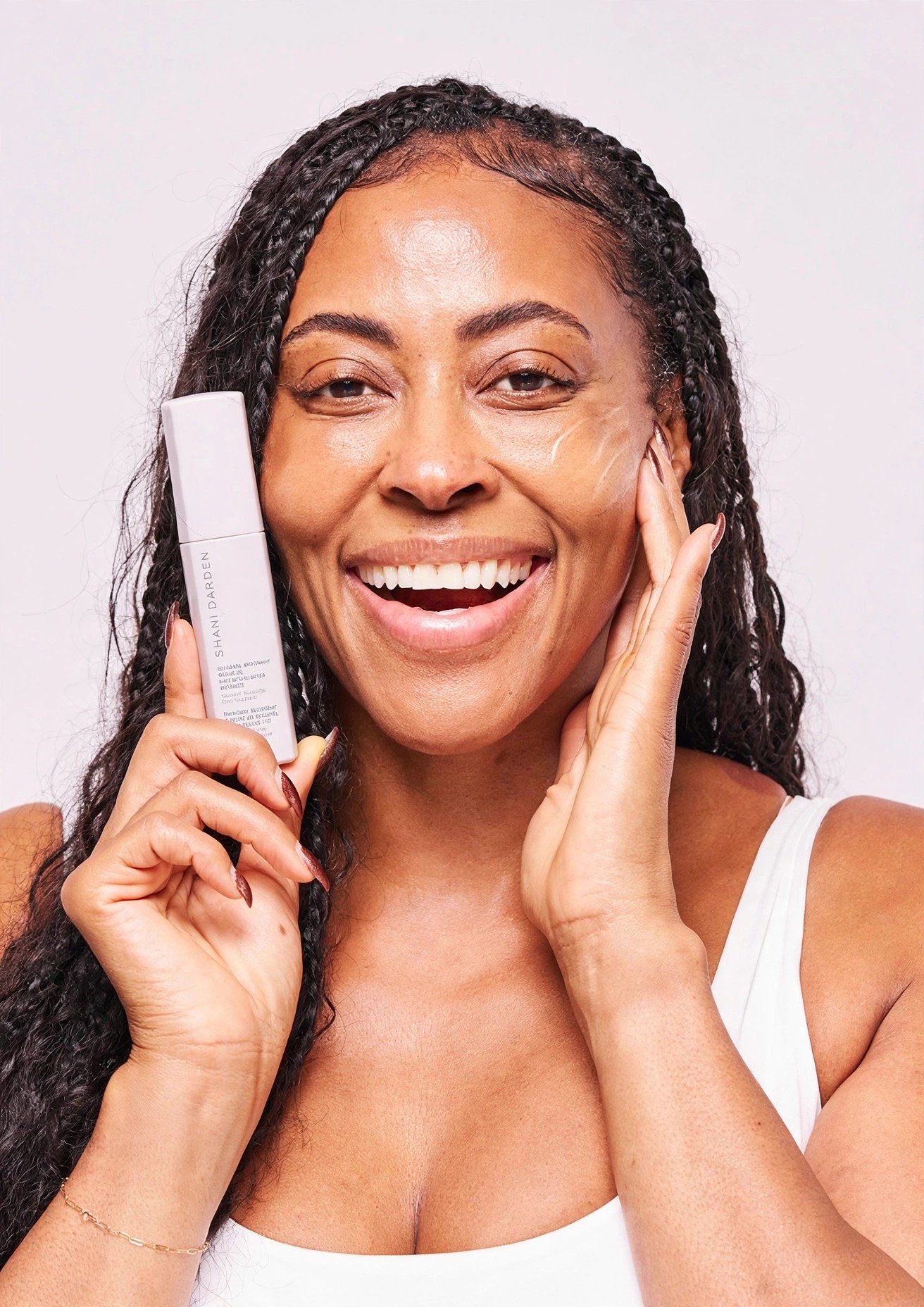 A smiling woman holds Retinol Reform beside her cheek.