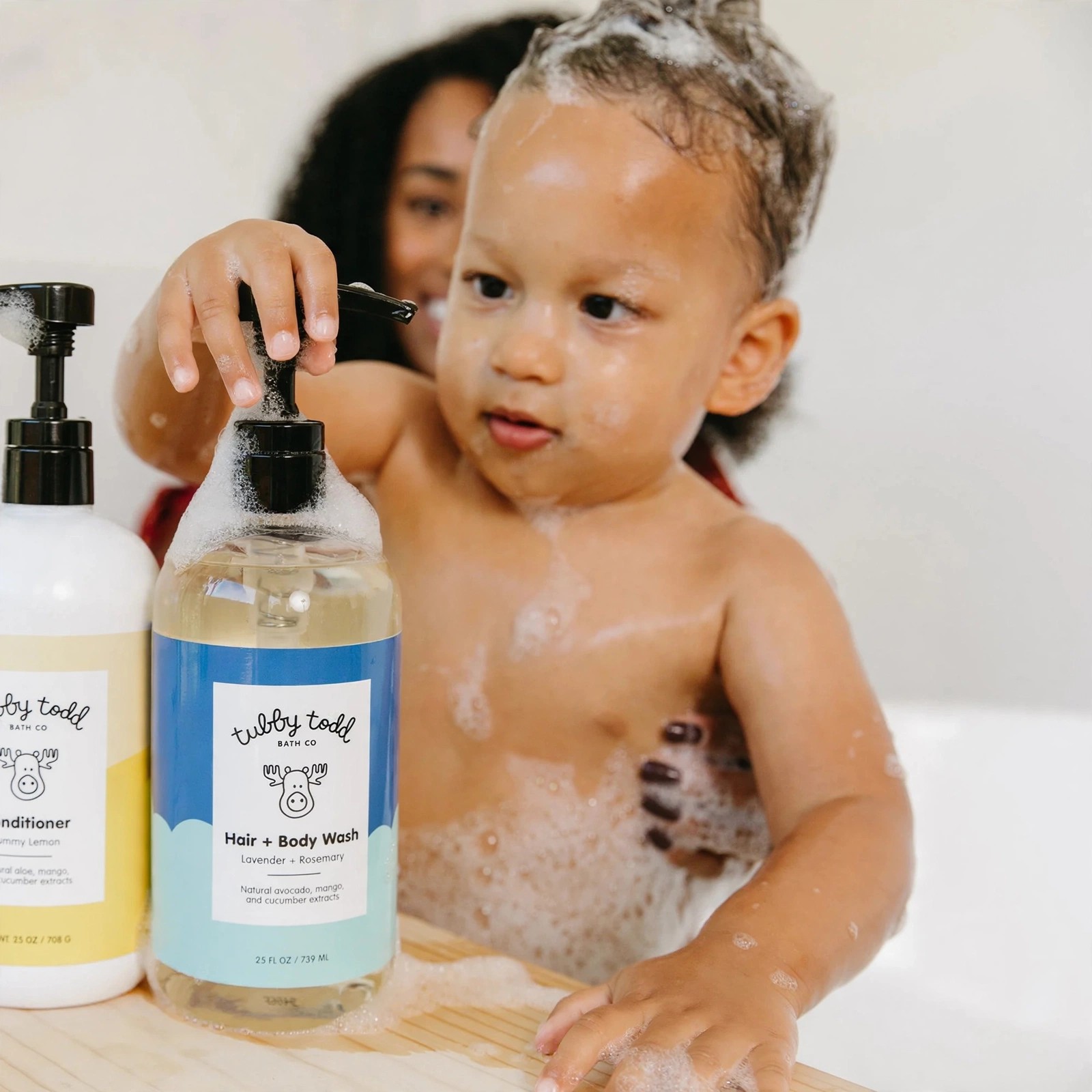 Toddler at bath time reaching for Hair and Body Wash.